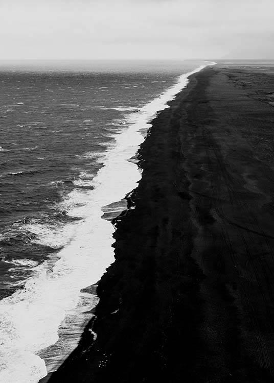  - Black and white aerial shot of the coast with a black beach and powerful waves.