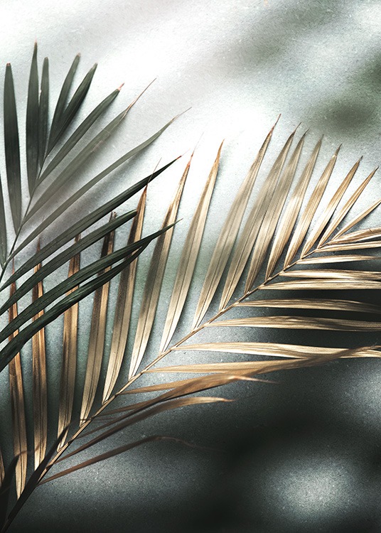  – Photograph of a pair of palm leaves in gold and green on a stone background