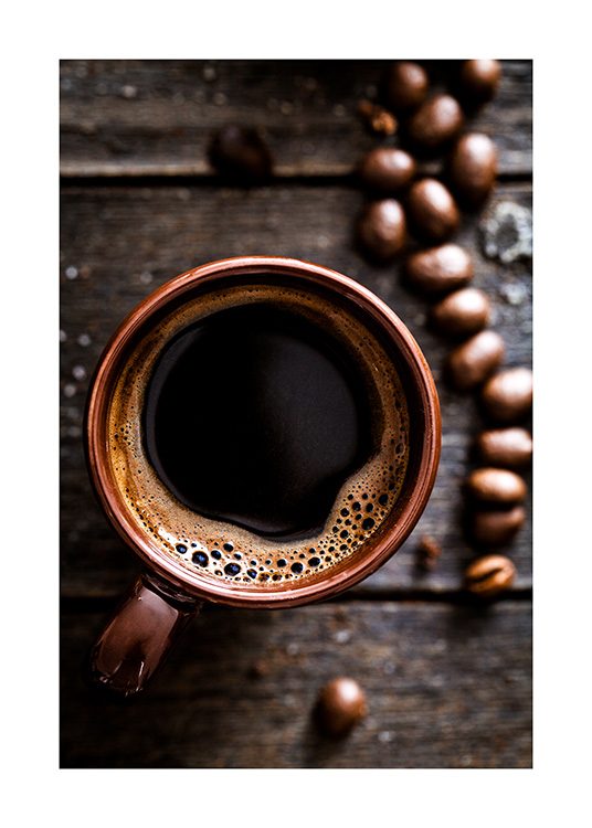  – Photograph from above of a cup of coffee on a wooden table, with coffee beans on the side