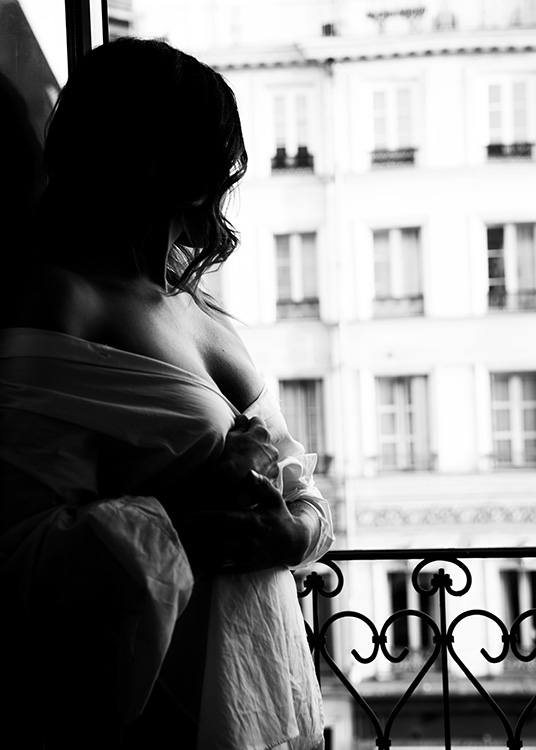 – Black & white photograph of a woman standing by the window 