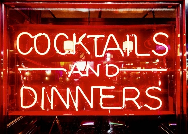 –Neon sign in bright red with a restaurant in the background. 