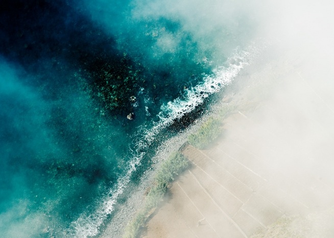 –Waves hitting the beach photographed from above. 