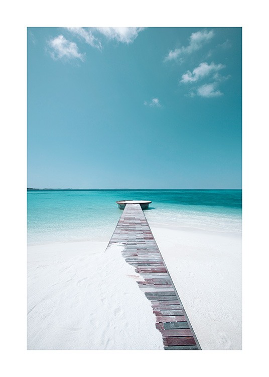 Photograph of a white sandy beach with a jetty reaching out into the blue sea