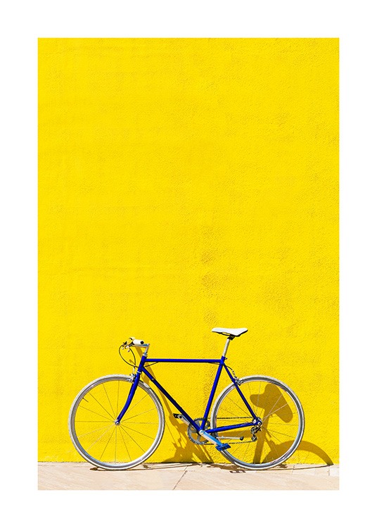 Blue bike standing in front of bright yellow wall