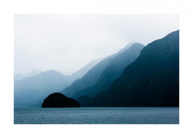 - Photograph of sea in front of blue mountains in layers with fog behind them