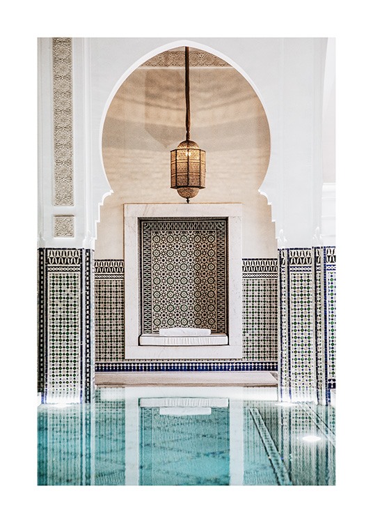  - Photograph of a gold lamp and a white arch with blue mosaic patterns behind a pool