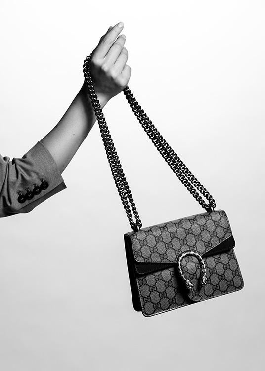  – Black and white photograph of a Gucci handbag behing held by a woman's hand