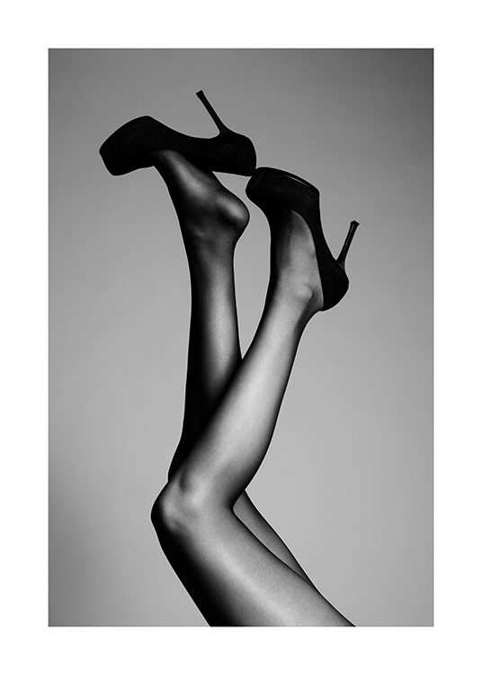  – Black and white photograph of a pair of legs stretched into the air, with black high heels