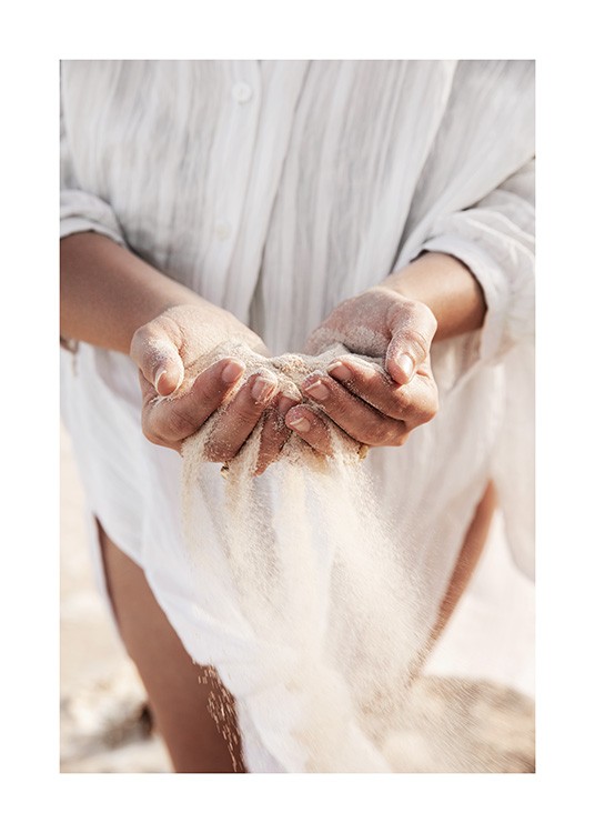  – Photograph of a woman holding sand in her hands, with her white linen shirt in the background