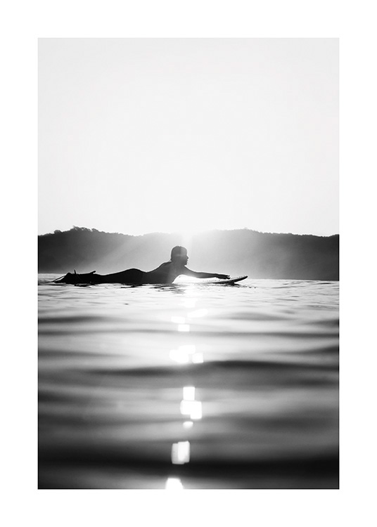  – Black and white photograph of a surfer laying on a surfboard in the water