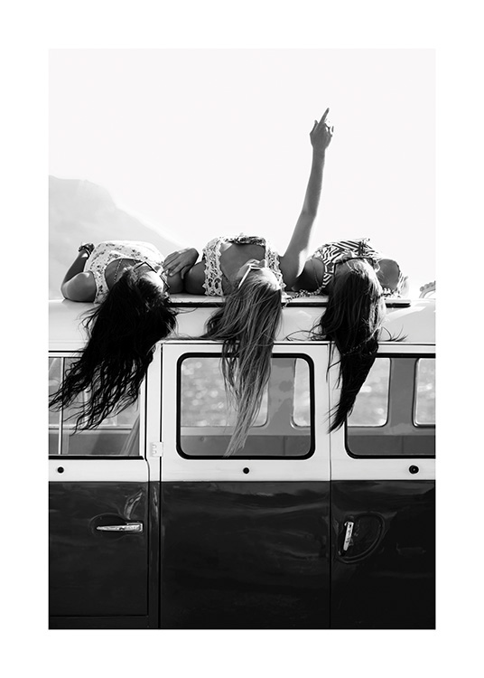  – Black and white photograph of three girls laying next to each other of the roof of a car