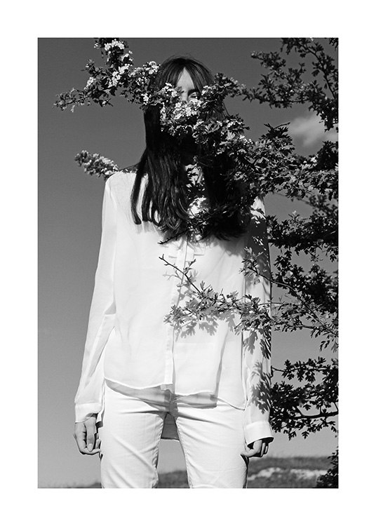  – Black and white photograph of a woman in white clothes, with a tree branch in front of her