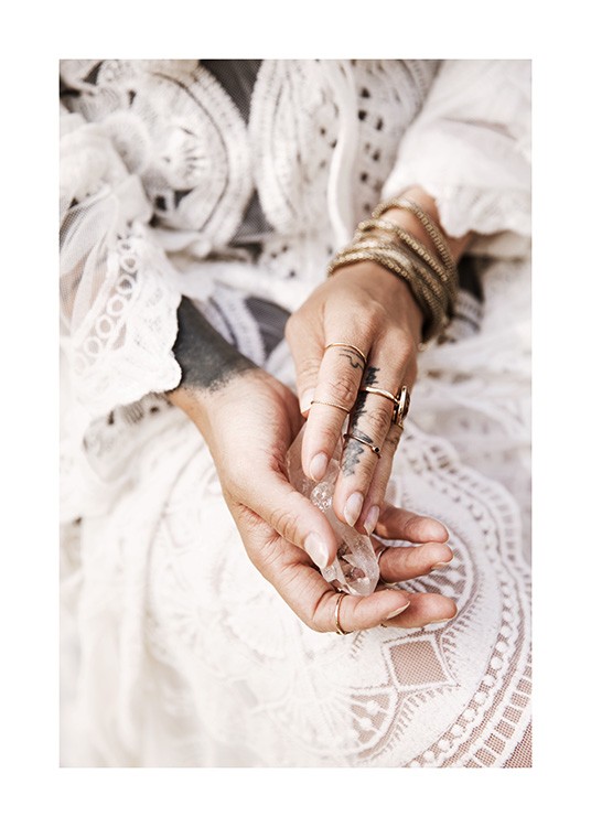  – Photograph of hands holding a crystal, with gold jewellery and a white lace dress in the background