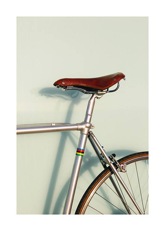  – Photograph of a bicycle in grey with a brown saddle and a green background behind it