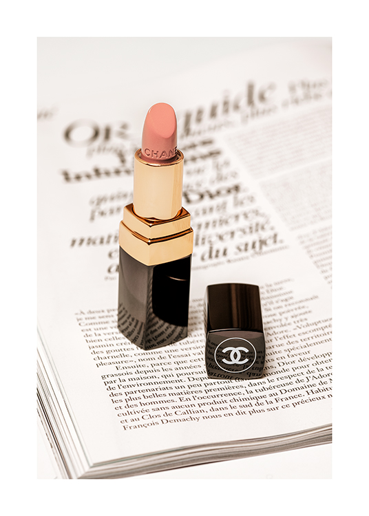  – Photograph of a Chanel lipstick in light pink with a book page underneath it
