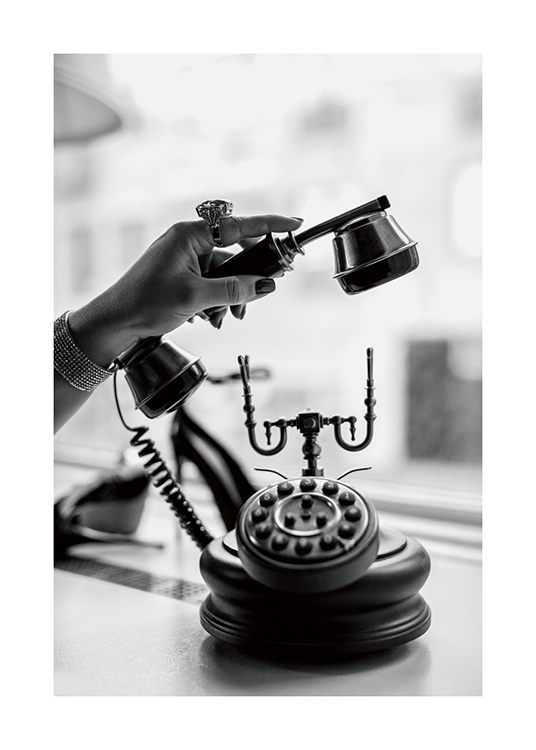  – A black and white photo of a woman picking up a vintage telephone while wearing a statement ring