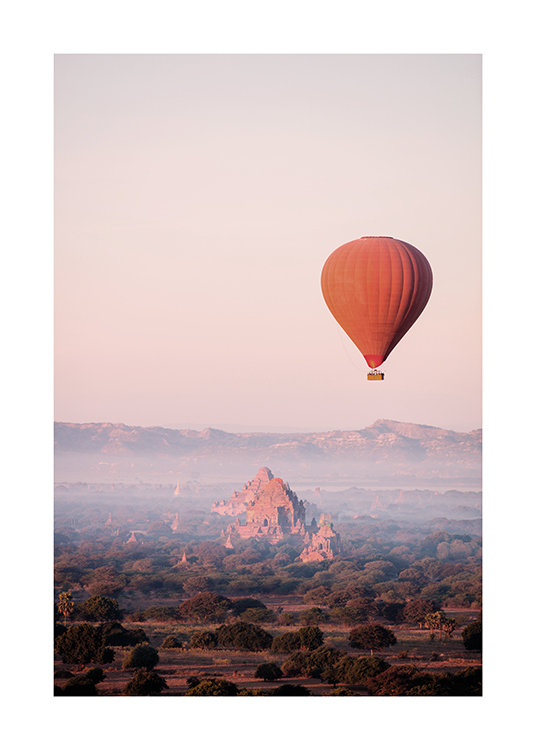  – Photograph of red hot air balloon in the air with a mountain and forest landscape in the background