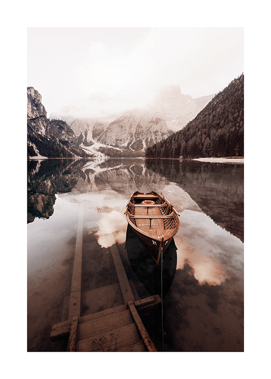  – Photograph of a still lake with a small wooden boat in it and snowy mountains in the background