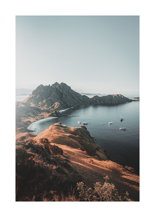  – Photograph of boats in the ocean next to large cliffs at Padar Island in Indonesia