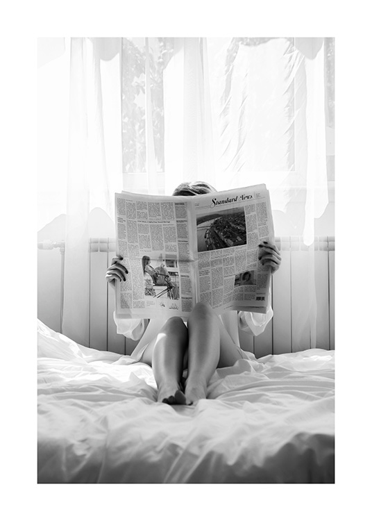  – Black and white photograph of a woman reading a newspaper in bed