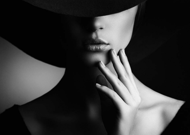  - Modern black and white fashion poster of a woman whose face is partially covered by a hat.